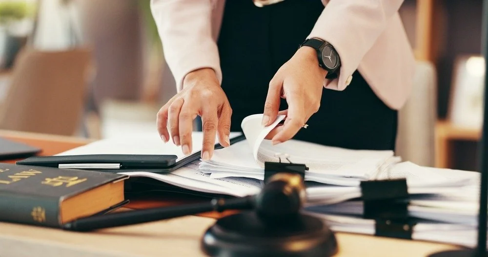 Abogada revisando expedientes junto a un mazo y un libro de leyes